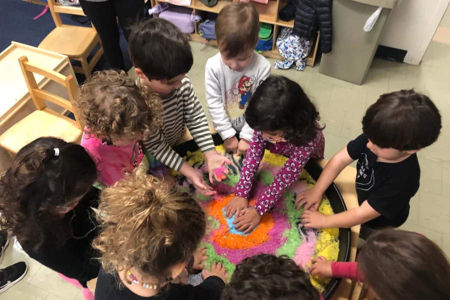 kids playing with colored sand in a classroom